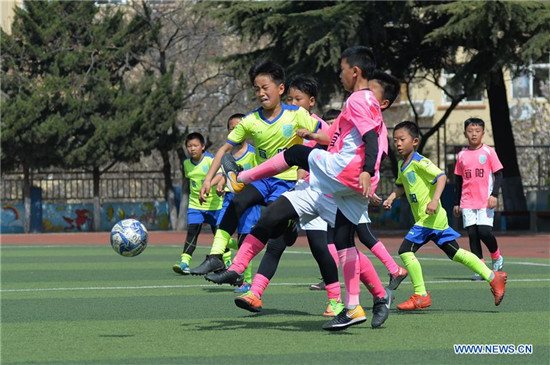 Pupils take part in football training in elementary school in Qingdao